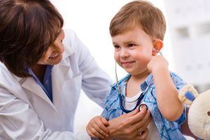 Senior female doctor examining happy child, smiling.